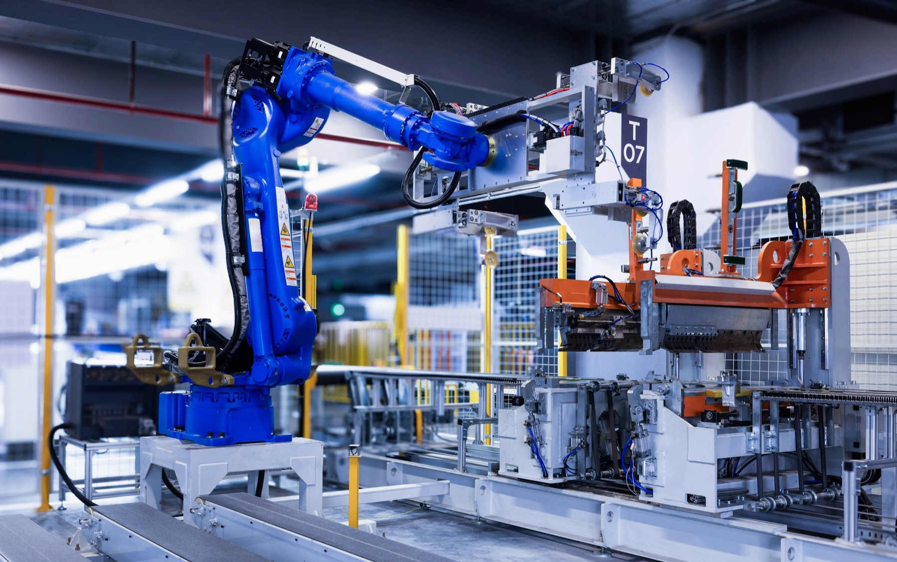 A blue industrial robot arm inside an integrated production cell