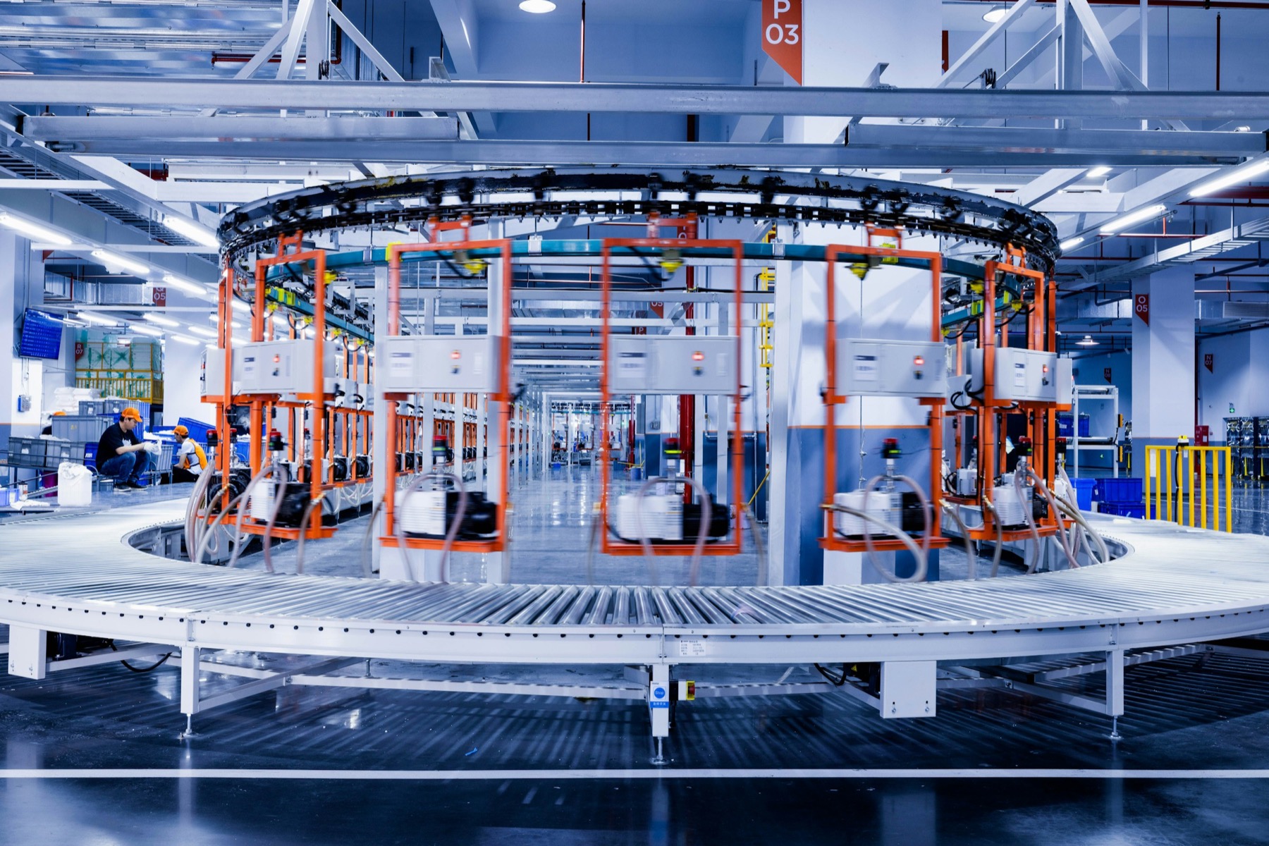A circular test rig on a factory floor with two workers beside it